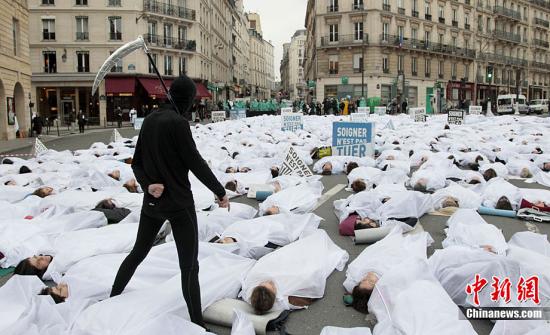 资料图：当地时间2011年1月25日，法国巴黎的卢森堡公园前法国人类生存联盟成员罩着白布躺在大街上抗议安乐死合法化法案。