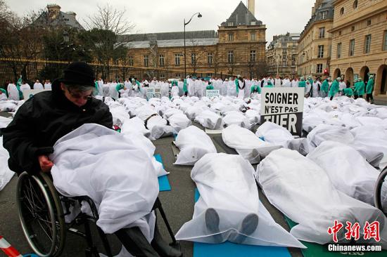 1月25日，法国巴黎的卢森堡公园前法国人类生存联盟成员罩着白布躺在大街上抗议安乐死合法化法案。