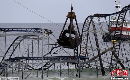 当地时间2013年5月14日，美国新泽西州，工人开始拆除搁浅在海滨高地的Jet Star过山车，该过山车是码头游乐园的标志性建筑，于2012年10月被超级风暴“桑迪”所摧毁吹入海中。