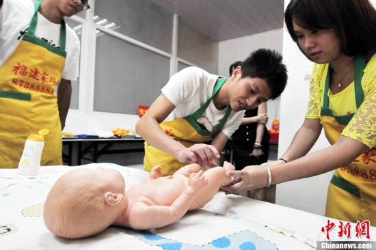 资料图：家政服务人员练习婴幼儿护理操作。
