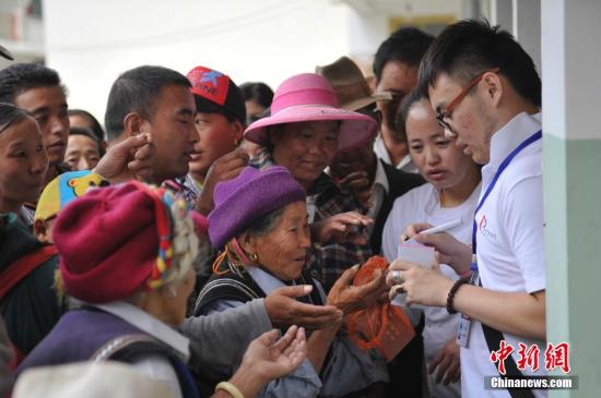 7月9日，志愿者为前来候诊的藏民挂号。近日，“同心·共铸中国心迪庆行”大型公益活动走进云南迪庆藏族自治州。由医务志愿者、社会爱心人士、高校志愿者等450余人组成的爱心团队深入香格里拉、维西、德钦3县乡镇、寺庙等26个义诊点为藏区民众提供直接的诊疗服务和健康咨询。中新社发 刘冉阳 摄