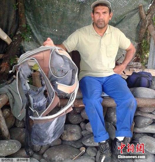 图为当地时间7月30日，留尼旺岛上的一名海岸清洁人员展示他找到的一个手提箱的残骸。