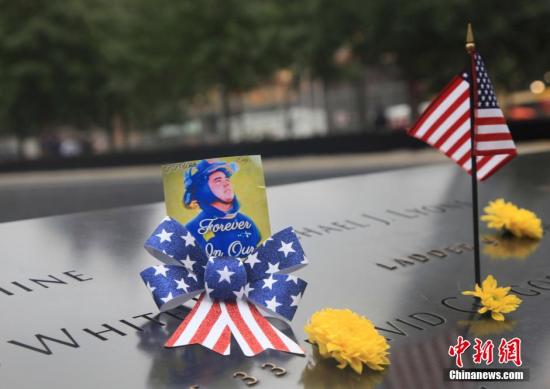 2015年9月11日，世贸遗址上摆放着鲜花和遇难者的照片。 <a target='_blank' href='http://www.chinanews.com/'><p align=