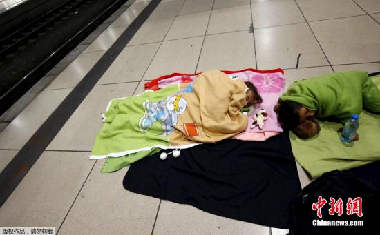两名来自叙利亚难民家庭的小朋友在法拉克福火车站的站台上睡着了，经过了漫长的跋涉，他们和父母终于幸运的搭上了从布达佩斯到法兰克福的火车。