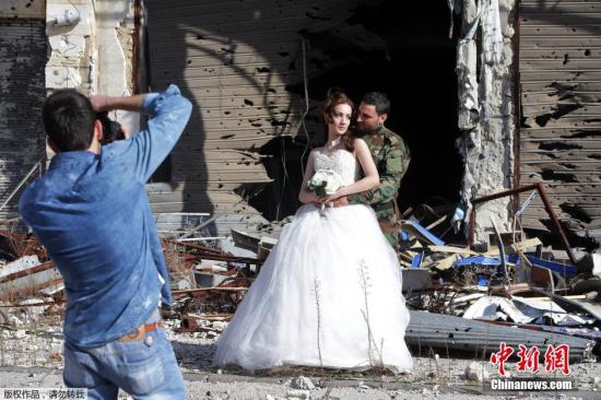 资料图：当地时间2月5日，叙利亚霍姆斯一对新婚夫妇Nada Merhi和Hassan Youssef 以饱受战争蹂躏被毁的建筑为背景拍摄婚纱照。