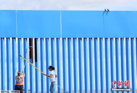 当地时间4月9日，志愿者在墨西哥墨西卡利参加“消除边界”艺术活动，将美墨之间的隔离墙粉刷成天空蓝，制造出墙体消失的视觉错觉。
