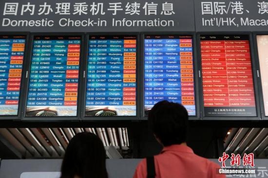 7月19日，乘客查看显示航班信息的电子屏。当日，北京“豪雨”来袭，市气象台发布今年首个暴雨蓝色预警。首都机场目前有接近100个航班处在延误或者取消的状态。截至16：00，首都机场计划执行1033架次，已执行913架次。 <a target=<em></em>'_blank<em></em>' href=<em></em>'http://www.chinanews.com/<em></em>'>中新社</a>记者 李慧思 摄