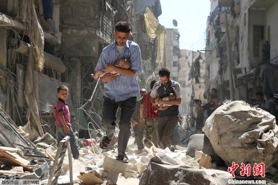 资料图：叙利亚民众行走在阿勒颇的废墟当中。