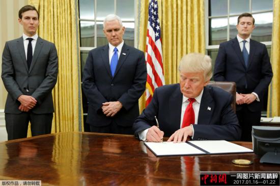 当地时间1月20日，新上任的美国总统特朗普坐在白宫椭圆形办公室内，签署下他任期内的第一批行政命令。在特朗普身后，站立着他的女婿兼总统高级顾问贾里德·库什纳、副总统彭斯，以及员工秘书长Rob Porter。