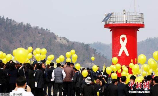 当地时间2017年3月28日，韩国珍岛，民众悼念“世越”号遇难者。为将“世越”号沉船运至木浦新港，打捞组正加速进行排水和除油工作。
