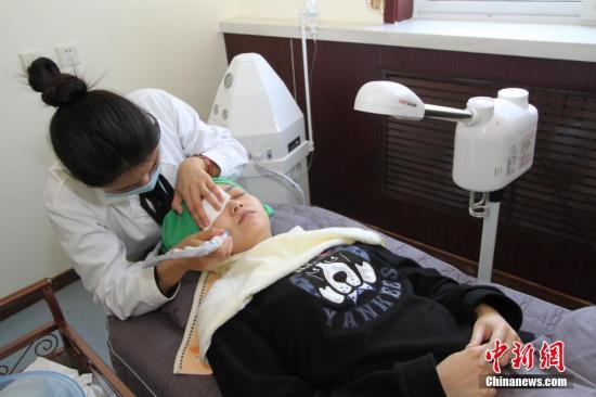 资料图：医师正在用冷热喷蒸脸器，对一位顾客进行脸部皮肤的祛痘清洁护理。