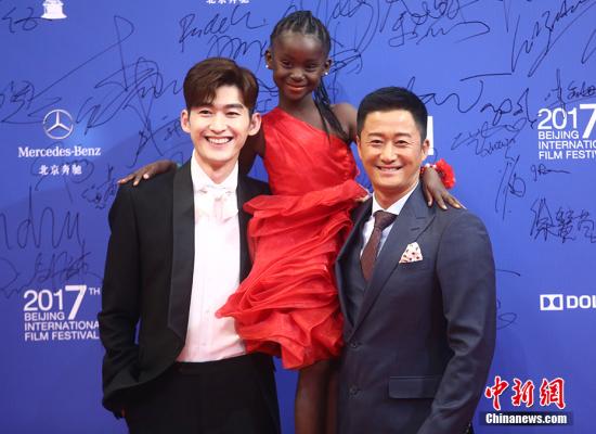 图为吴京张翰代表《战狼2》一同现身面带微笑，两个人更是手臂对手臂将来自非洲的小朋友托举起来。 <a target=