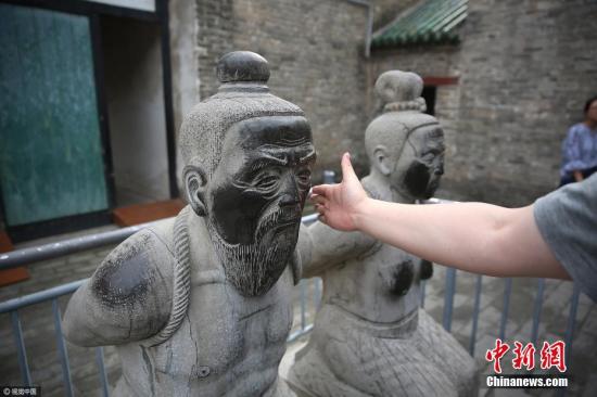 安徽亳州花戲樓景區內的岳武穆王廟門前，游客掌摑秦檜跪像。圖片來源：視覺中國