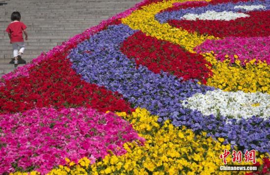 5月15日，游客经过北京天坛公园“一带一路”主题花坛。北京市属公园为“一带一路”国际合作高峰论坛共布置了十余处“花境丝路”主题花坛，用花量达180万株(盆)。中新社记者 刘关关 摄