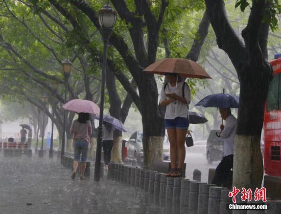 6月16日，广西柳州市遭暴雨侵袭，民众在风雨中出行。 中新社记者 朱柳融 摄