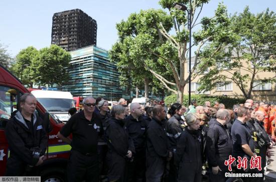 6月20日消息，英国警方称，在日前发生的伦敦“格伦菲尔塔”公寓楼大火中，已经有79人“推定死亡”。这一数据还有可能发生变化。6月19日，英国民众举行活动，为此次事件中的遇难者默哀一分钟。图为肯辛顿附近消防员为遇难者默哀，身后不远处就是事发大楼。