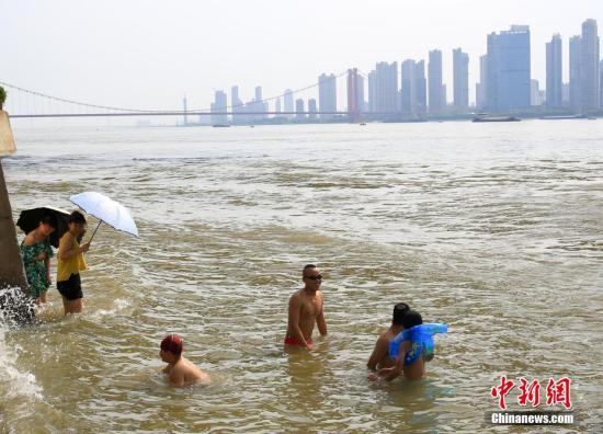 7月25日，武汉武昌江边，市民打伞遮阳站在水中降温。当日，武汉中心气象台发布高温红色预警。武汉、十堰、襄阳等9个地市高温突破40℃。未来三天，湖北省大部地区最高气温为37℃到40℃，局部地区最高气温将达到41℃到42℃。 <a target='_blank' href='http://www.chinanews.com/'>中新社</a>记者 张畅 摄