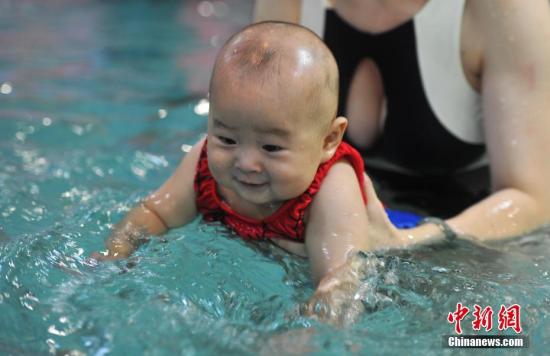 8月5日，江西南昌高温天气持续，年轻妈妈带着自己的孩子在一家婴幼儿游泳馆，戏水游泳，享受清凉。 /p中新社记者 刘占昆 摄