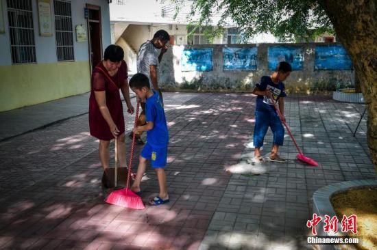 海口市龙头小学二年级苏晓虎、四年级付豪一起上劳动课，他们在老师的指导下清扫教室和教学楼前落叶。骆云飞 摄