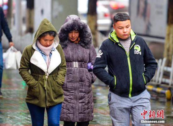 10月6日，新疆乌鲁木齐市街头，外出民众穿着厚重的冬衣御寒。 记者 刘新 摄