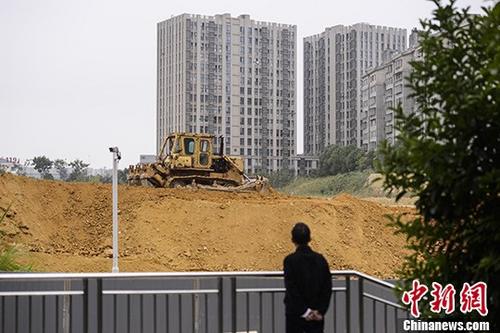 市民观望湖南长沙一楼盘工地上的推土机作业。 中新社记者 杨华峰 摄