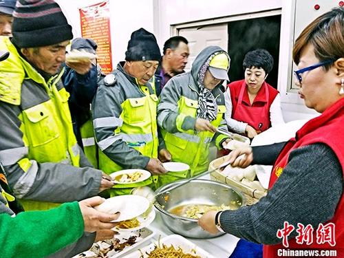 资料图：哈尔滨“爱心粥铺”免费为环卫工和孤寡老人开放，志愿者为环卫工人和老人打饭。 <a target=