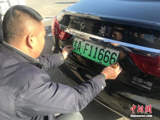 A resident in Changchun, Northeast China's Heilongjiang Province, installs a car license plate for his new energy vehicle on Nov. 20, 2019. (Photo/China News Service)