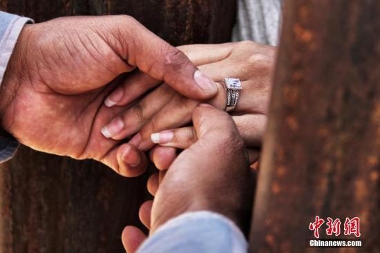 近日，墨西哥华雷斯市，因美墨“边境墙”分开的亲友参加“让梦想继续”活动，完成3分钟的团聚。Rogelio隔着墙为Miriam戴上戒指，完成婚礼。