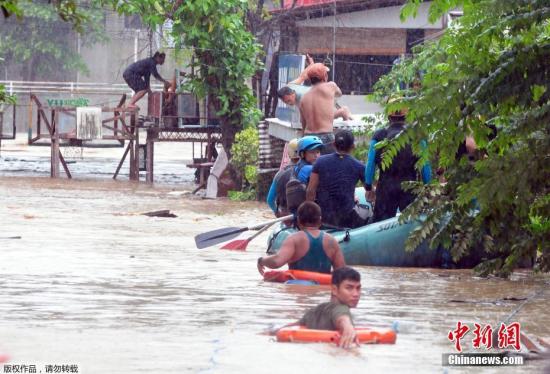 菲律宾卡加廷德奥罗港口城镇遭水淹严重，救援人员用橡皮艇把被困居民从屋子里解救出来。