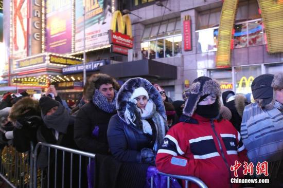 当地时间2017年12月31日，纽约时报广场寒风中等待跨年的人们。当日，纽约时报广场举行一年一度的跨年庆典，尽管当天气温降至零下十度以下，仍吸引了成千上万的人们在严寒中迎接新年。中新社记者 廖攀 摄