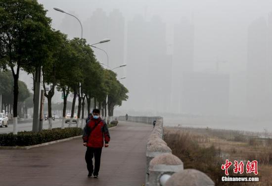 1月20日，武汉市民戴口罩雾霾天出行。当日，武汉再次发布雾霾黄色预警。受气象条件影响，预计中、重度污染天气还将持续。 中新社记者 张畅 摄