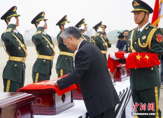 图为中国驻韩国大使邱国洪为志愿军烈士遗骸覆盖国旗。 中新社记者 吴旭 摄 图为中国驻韩国大使邱国洪为志愿军烈士遗骸覆盖国旗。 中新社记者 吴旭 摄