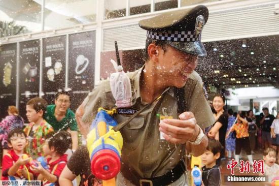 资料图：当地时间2018年4月15日，泰国曼谷民众玩水枪打水仗庆祝泼水节，迎接泰国新年到来。图为曼谷街头，负责安保的警察也没能逃过水枪的喷射。