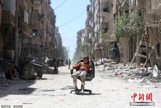 相较于成年人的“自娱自乐”，战争对于叙利亚儿童的隐形伤害远比肉体上的伤害更难以治愈。联合国救援人员在冲突严重地区调查发现，98%的家长认为自己的孩子出现心理和情绪问题。图为2018年4月16日，坐在废墟中的一个叙利亚孩子。