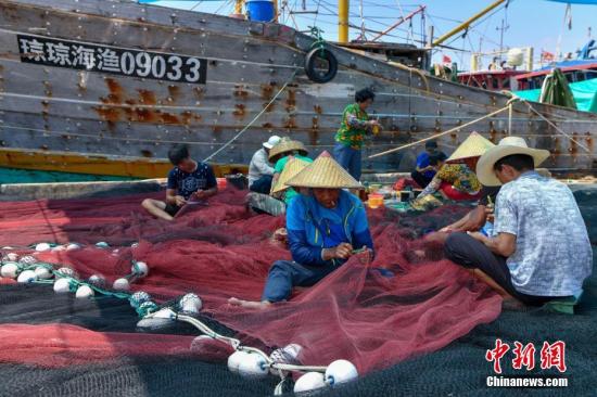 图为海南省琼海市潭门中心渔港的渔民正在修补渔网。<a target=