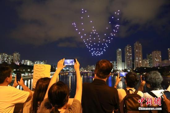 6月30日晚，为庆祝香港回归祖国21周年、国民教育沙田区委员会成立10周年及为第8届沙田节揭开序幕，香港沙田城门河上空举行全港首次100架无人机户外光影汇演。图为本次汇演吸引了不少民众前来观赏。中新社记者 谢光磊 摄