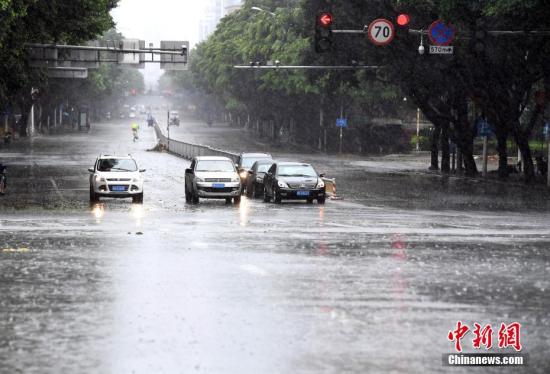 资料图：民众在暴雨中开车出行。刘可耕 摄