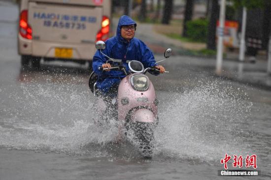 资料图：海南昌江民众冒雨涉水出行。中新社记者 骆云飞 摄