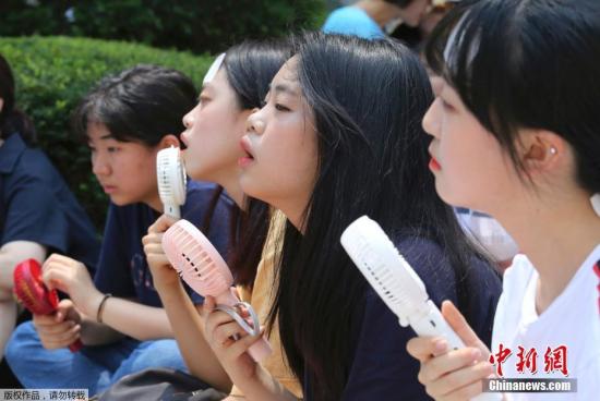资料图：2018年，韩国应酷暑高温，首尔街头手持小风扇纳凉的人群。