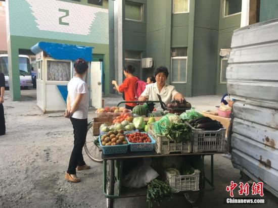 有人在街边卖蔬菜和水果。朝鲜的粮食、瓜果蔬菜是国家供应，能满足大部分需求，不够的话可以去商店或市场购买。 中新网记者 邱宇 摄