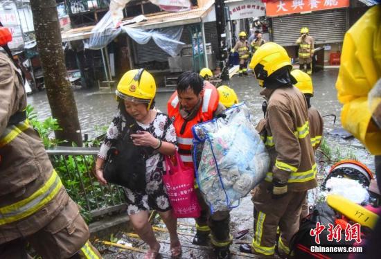 9月16日，强台风“山竹”当日逼近香港，消防员正协助居民离开受水浸影响的地区。中新社记者 麦尚旻 摄