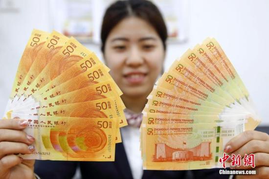 资料图：中国人民银行发行的人民币发行70周年纪念钞与改革开放40周年纪念币。张云 摄