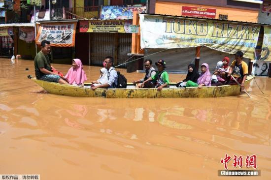 资料图：2019年2月24日，印尼西爪哇省万隆，西大鲁河沿岸遭洪水侵袭。图为当地街道被淹，民众划船出行。