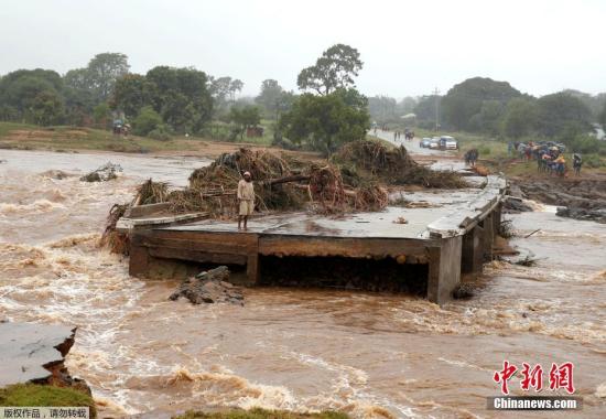 当地时间2019年3月18日，津巴布韦奇马尼马尼，强热带气旋“伊代”席卷当地带来洪灾，洪水暴涨冲毁桥梁，一名男子站在坍塌的大桥边上。