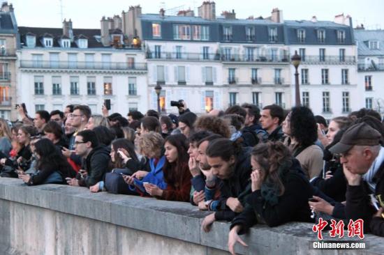 当地时间4月15日晚，法国首都巴黎的著名地标巴黎圣母院发生大火，受损严重。巴黎圣母院大火引发民众高度关注，众多民众在现场附近聚集。/p中新社记者 李洋 摄