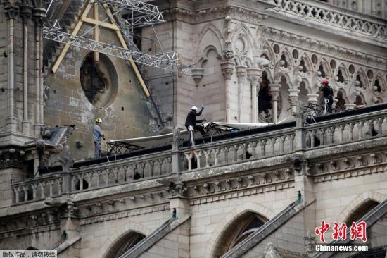 资料图：工人们为遭大火重创的巴黎圣母院安装了临时防水布，以保护圣母院免受雨水的破坏。