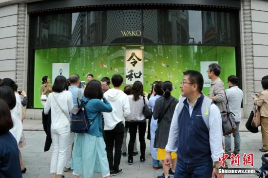 资料图：东京街头，一家商店橱窗的“令和”字样吸引民众合影留念。 <a target='_blank' href='http://www.chinanews.com/'>中新社</a>记者 吕少威 摄