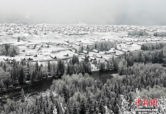 5月15日，经过一夜的降雪，地处新疆阿勒泰山区的古老村落——禾木村，山间树木、河岸两边、图瓦木屋尖顶上覆盖了一层洁白的雪花。清晨时分，安静的村落里升起袅袅炊烟，整个村落仿佛在一夜之间重回“水墨世界”，诗意盎然，美到令人窒息。王希凤 摄