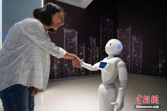资料图：一名参观者与5G+智能机器人“小5”握手。/p中新社记者 贺俊怡 摄