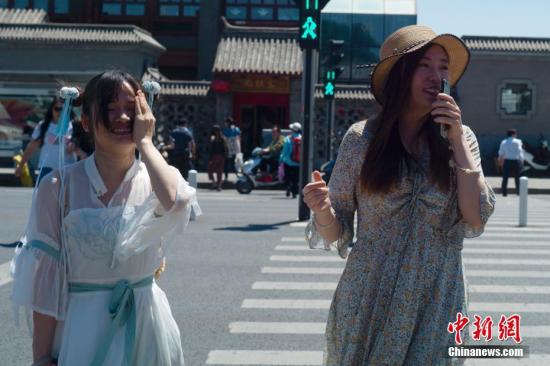 资料图：5月21日，北京天气晴晒，最高气温达31℃，两位姑娘走过人行横道。<a target='_blank' href='http://www.chinanews.com/'>中新社</a>记者 盛佳鹏 摄